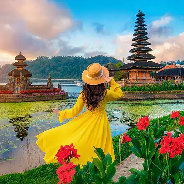 Woman in a yellow dress looking out at the iconic Ulun Danu Beratan temple in Bali.