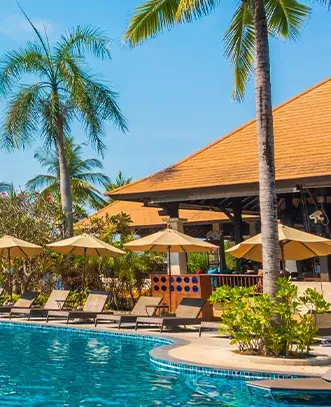 Relaxing poolside lounge chairs and tropical palm trees at a luxury resort, a key highlight of our bali holiday tour package.