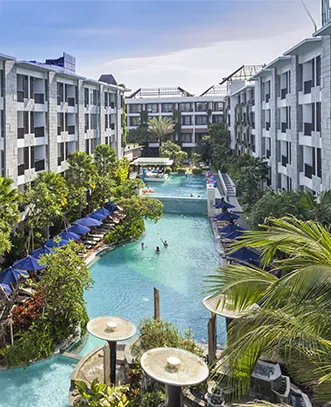 A beautiful tropical resort in Bali with a large pool and blue sun umbrellas, included in our premium international tour