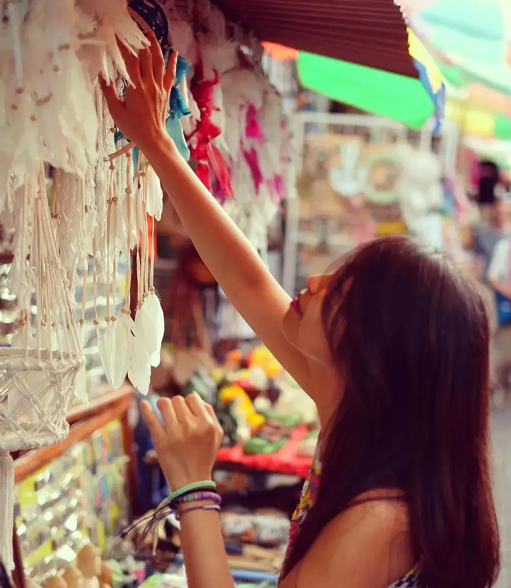 Explore the local culture and find unique treasures in Bali with this image of a woman shopping for handicrafts.
