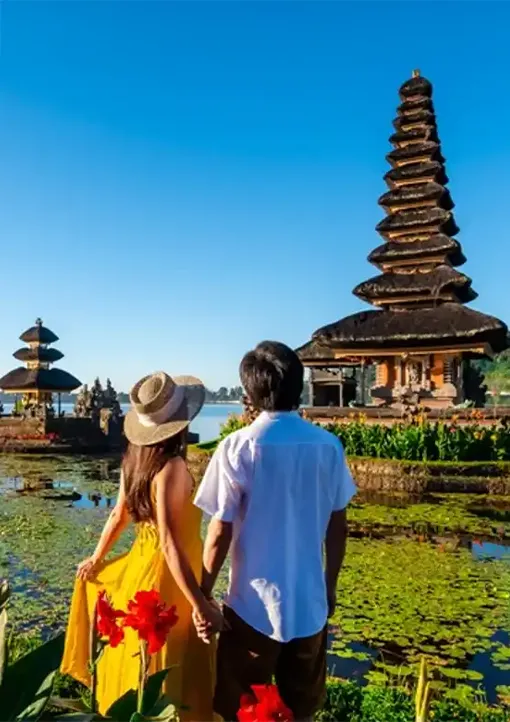 A romantic couple in traditional attire viewing the Ulun Danu Bratan temple, a highlight of our premium bali tour packages.