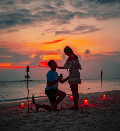 Romantic honeymoon couple embracing on a Bali beach at sunset, with golden light reflecting on the water.