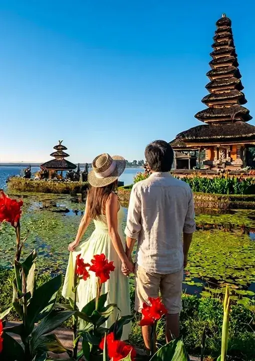 A romantic couple in traditional attire viewing the Ulun Danu Bratan temple, a highlight of our premium bali tour packages.