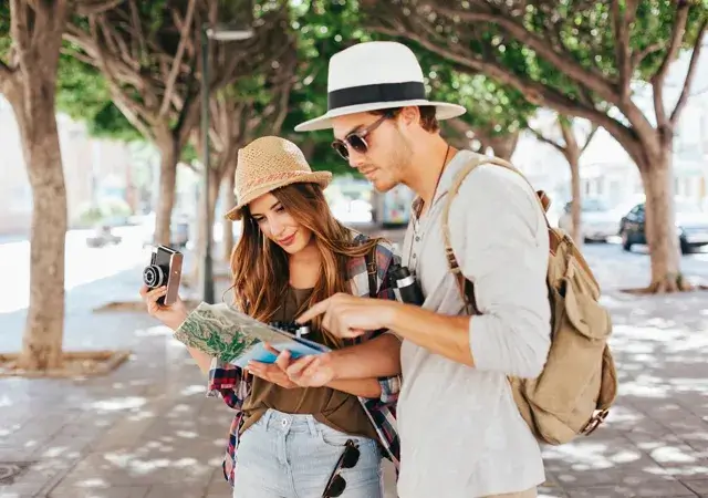 Couple exploring Bali, studying a map and tourist guide while considering Bali tour packages for their adventure.