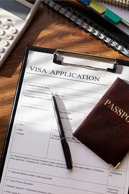 A Dubai visa application form with a passport and pen on a wooden desk, representing Adeeba’s 99% visa success rate.