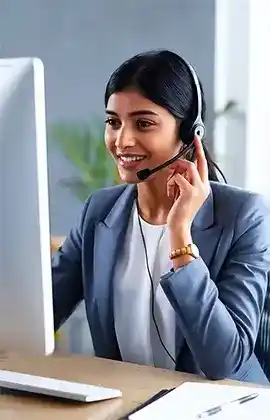 A woman with a headset sits at a desk, providing 24/7 travel support for Indian travelers.