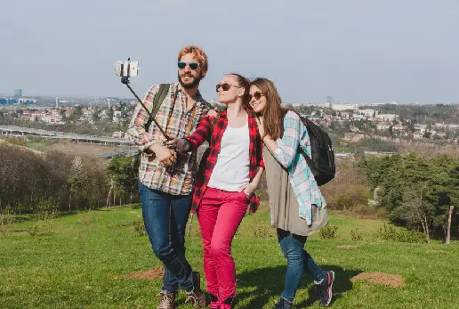 A group of three people happily taking a selfie with a selfie stick, enjoying their time together.