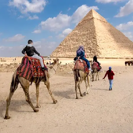 Tourists on camels in front of the pyramids, highlighting a memorable moment from an Egypt international tour package.