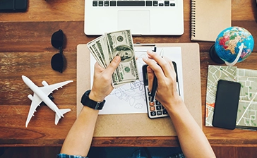 A traveler managing finances and flight plans on a wooden desk, perfect for planning a Budget friendly singapore tour package.