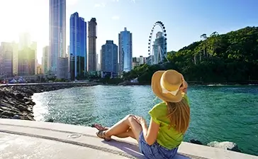 A traveler in a sun hat overlooking the stunning Singapore city skyline and Flyer, representing a Luxury singapore tour package.