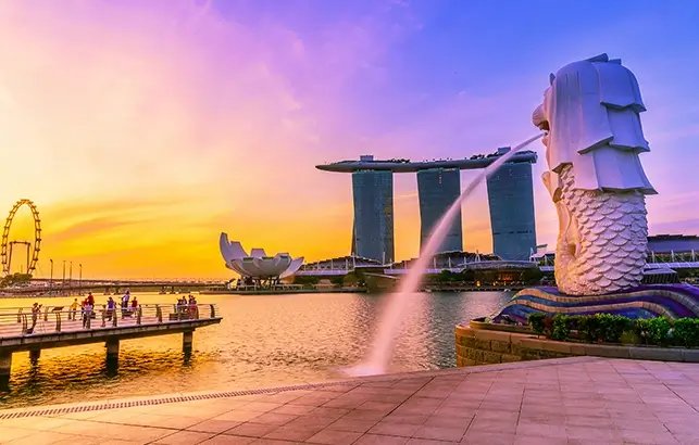 An aerial view of the Marina Bay Sands, ArtScience Museum, and the Singapore city skyline under a clear blue sky