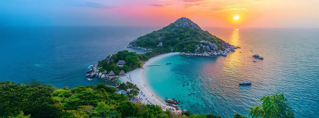 Aerial view of Koh Samui island at sunset with turquoise waters, white sandy beach, lush green hills, and colorful sky over the ocean.