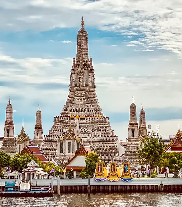 Tourists visiting the intricately decorated porcelain spires of Wat Arun temple in Bangkok.