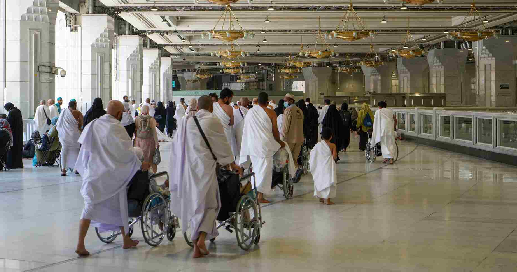 Umrah pilgrims and worshippers in the spacious, well-lit indoor area of a mosque.